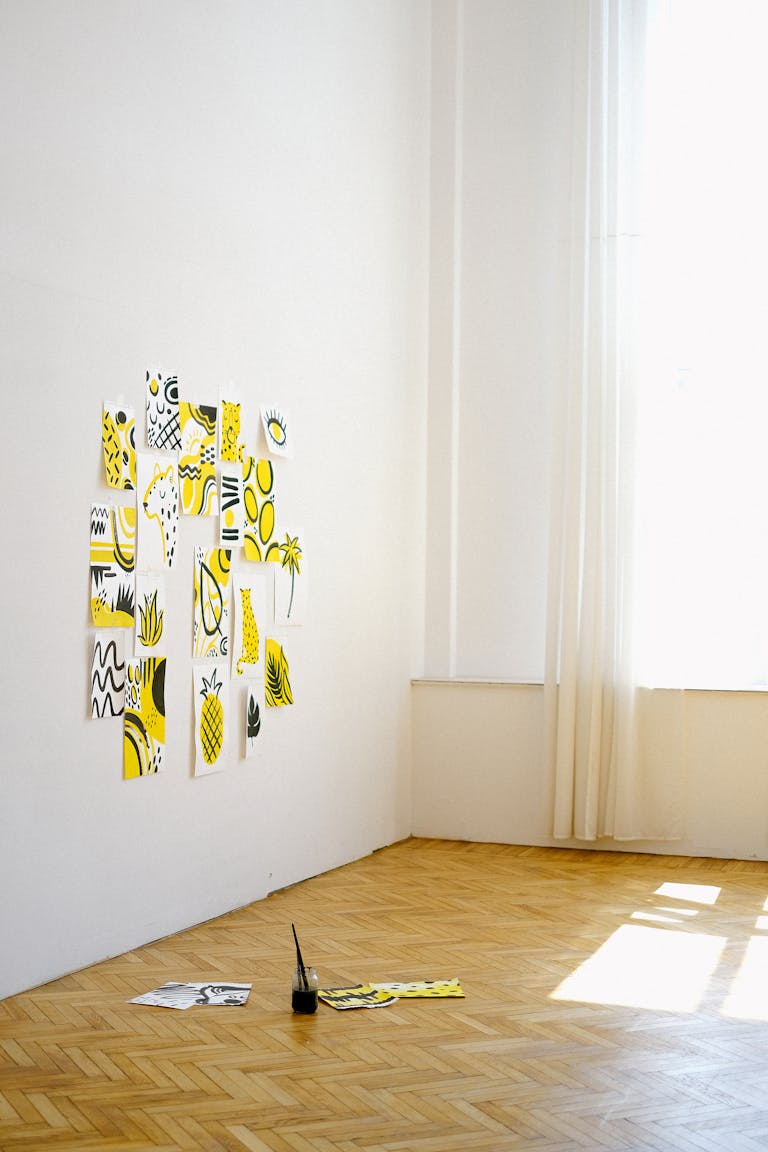 Creative art setup with abstract yellow and black sketches on white walls in a bright studio.